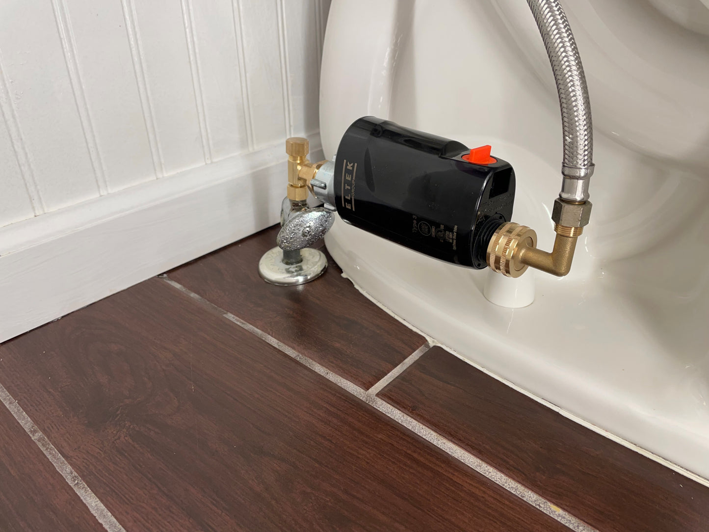 E-WaterBlock installed in a horizontal orientation on a toilet, connected directly to the stop valve with 3/8" brass adapter fittings