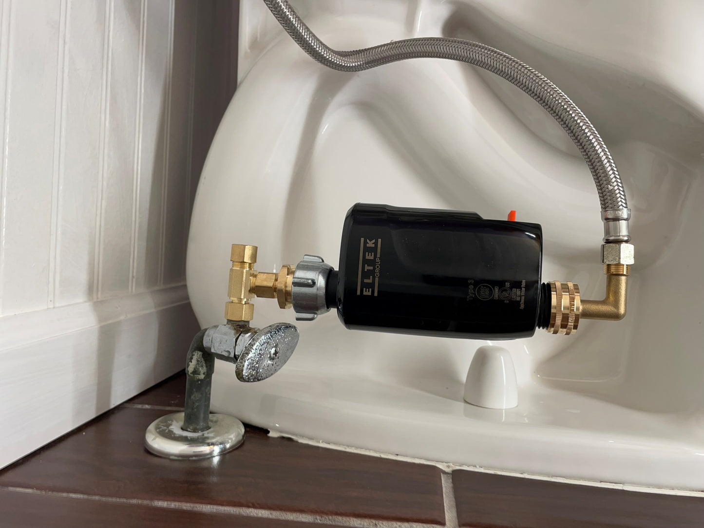 Electronic WaterBlock point-of-use smart water monitor installed on a toilet. Tracks water flow and consumption volume while detecting and shutting off micro to macro leaks.