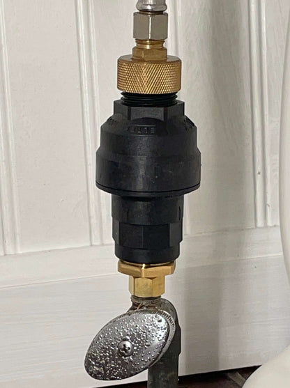 A black, hard plastic water leak detection device installed on a toilet to detect and stop leaks. The device is connected to the supply valve and to the toilet tank with 3/8" brass fittings. The device uses a sensor to detect water leaks. If a leak is detected, the device will activate the shutoff valve to prevent flooding and water damage. Automatic shutoff, 100% mechanical.